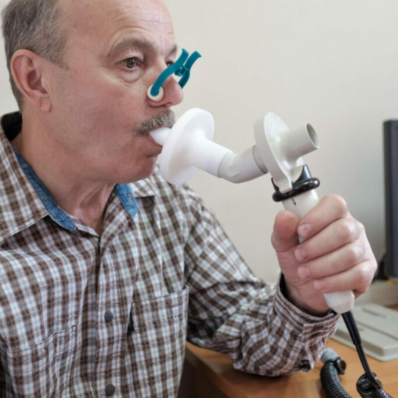 aelterer-hispanischer-mann-der-die-atmungsfunktion-durch-spirometrie-testet